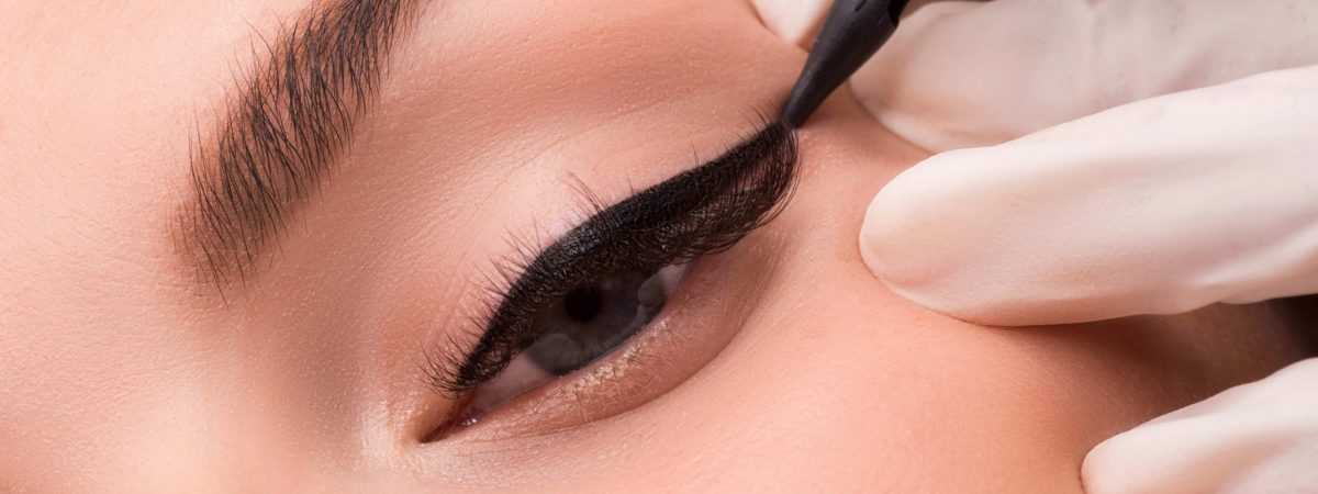 Permanent eye makeup close up shot. Cosmetologist applying tattooing of eyes. Makeup eyeliner procedure.